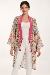 Birdsong Kimono in an ivory bird and floral print with pink borders and tassels, front view worn over a white top and trousers