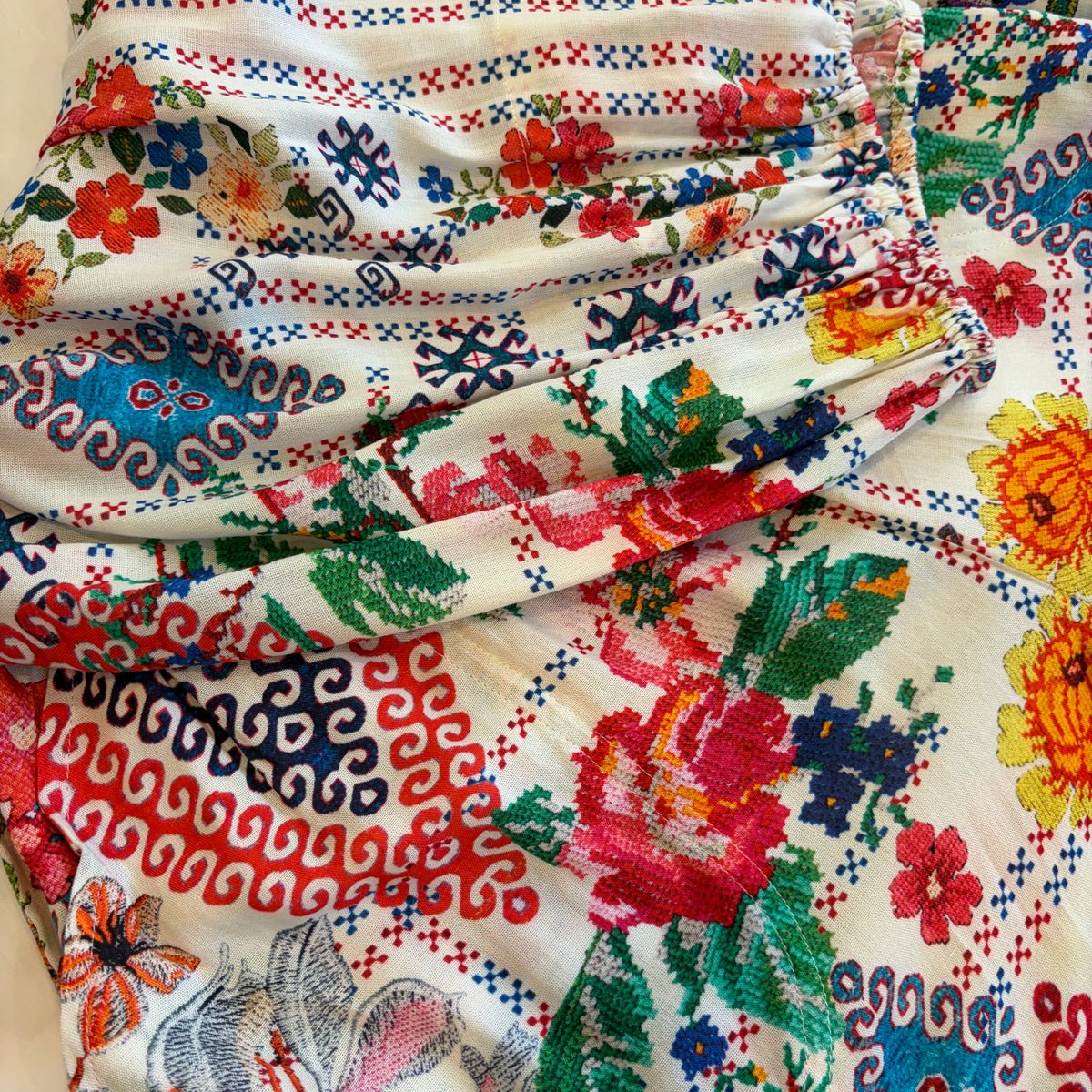 Cita Jumpsuit in ivory floral print viscose rayon, close view of gathered fabric with red roses, blue motifs and green leaves