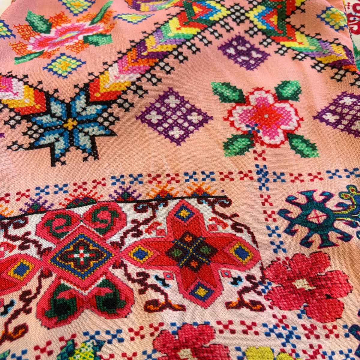 Cita Jumpsuit in floral and geometric print viscose rayon, close view of the fabric with pink borders and blue star motifs