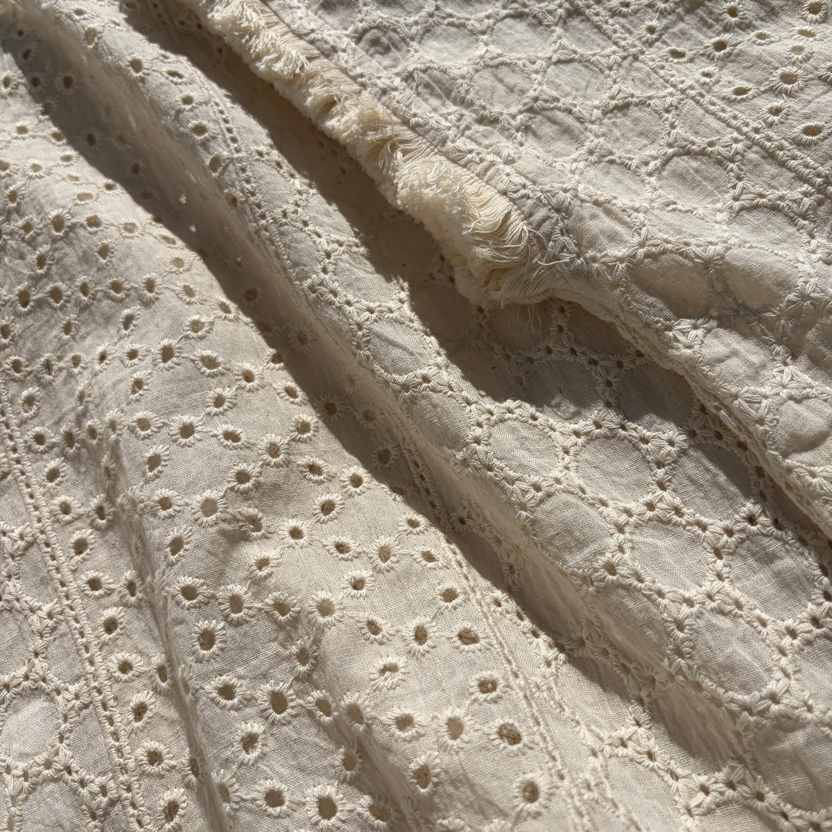 CJ-117 Top in natural cream, close view of the embroidered fabric and fringed sleeve edge