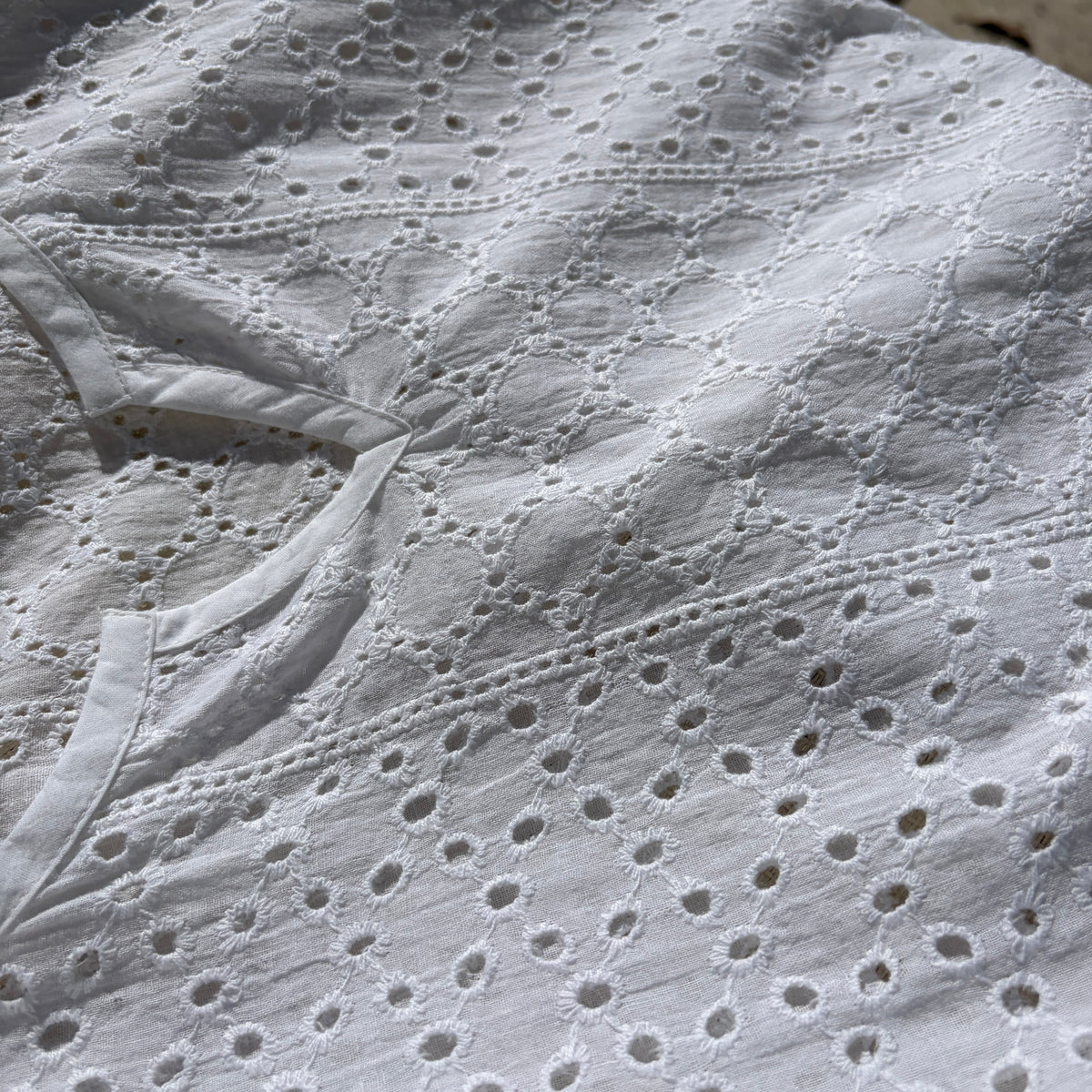 CJ-117 Top in white, close view of the notched neckline and oval eyelet embroidery