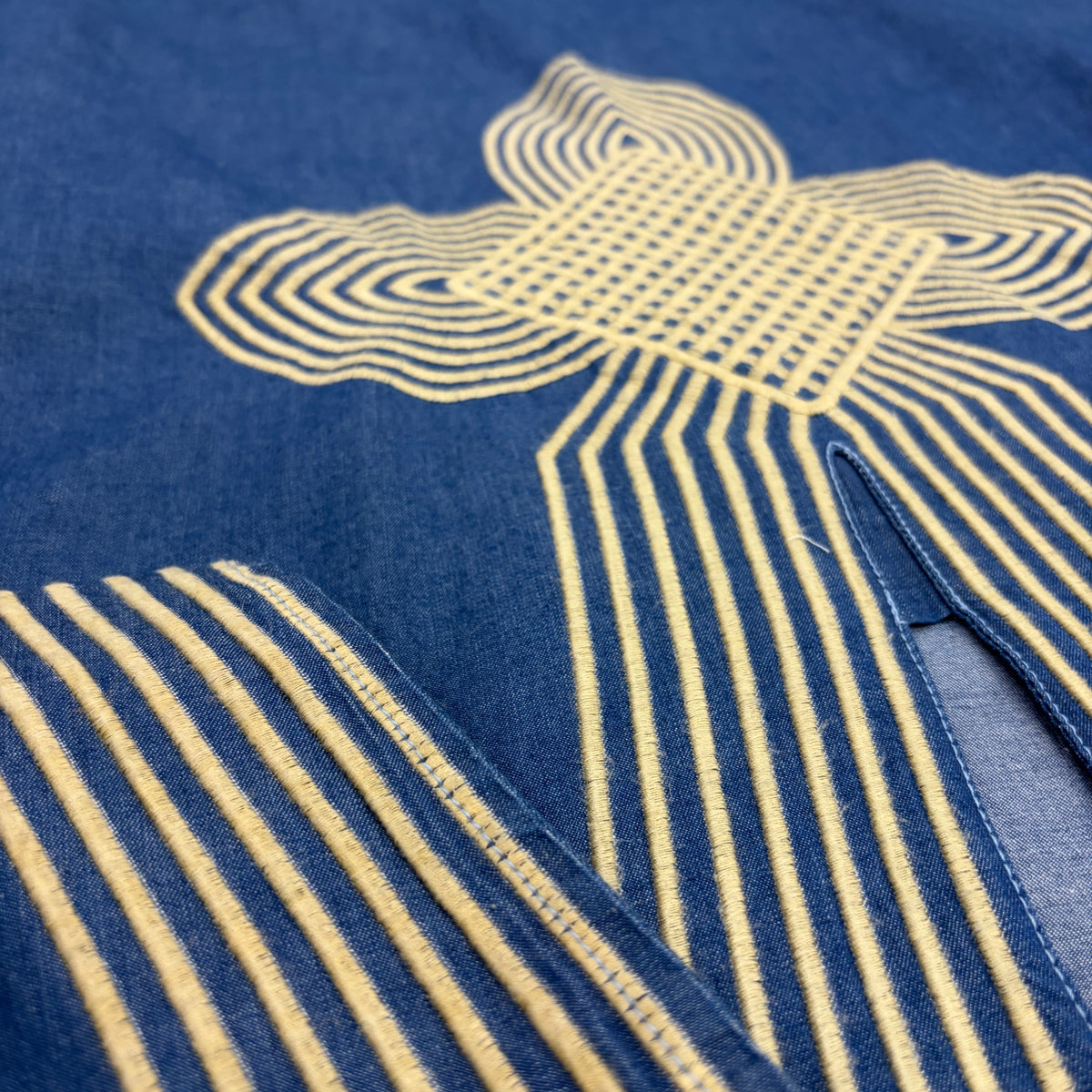 CJ-12 Egyptian Denim Dress, close view of indigo fabric and raised pale gold geometric embroidery around the neckline and sleeve border