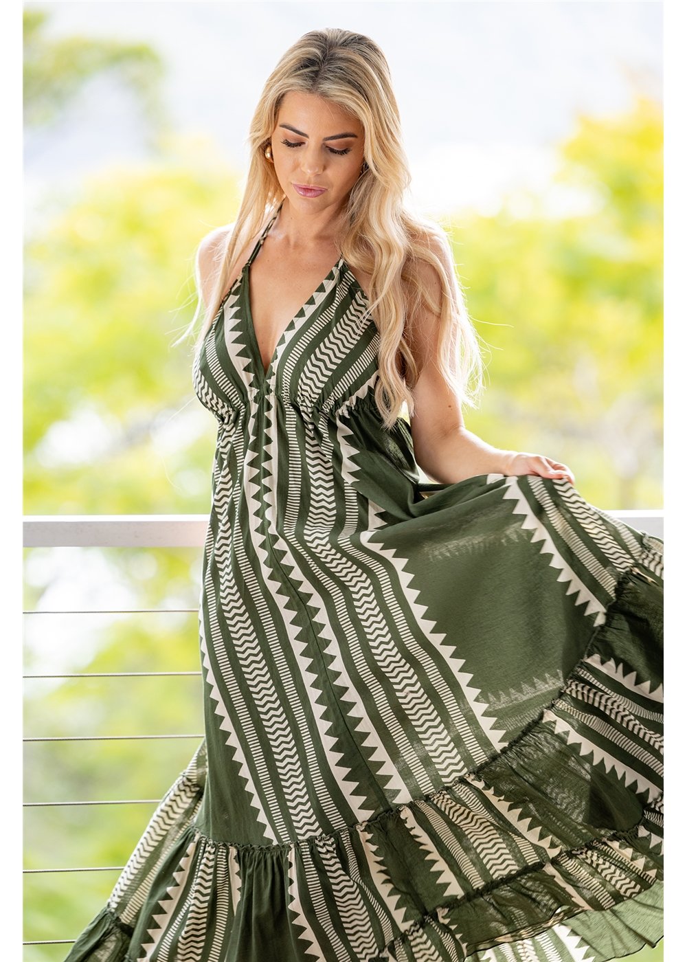 Karri Cotton Bikini Tie Halter Dress in olive green and cream geometric cotton, front view with the skirt held out to show the gathered hem and print