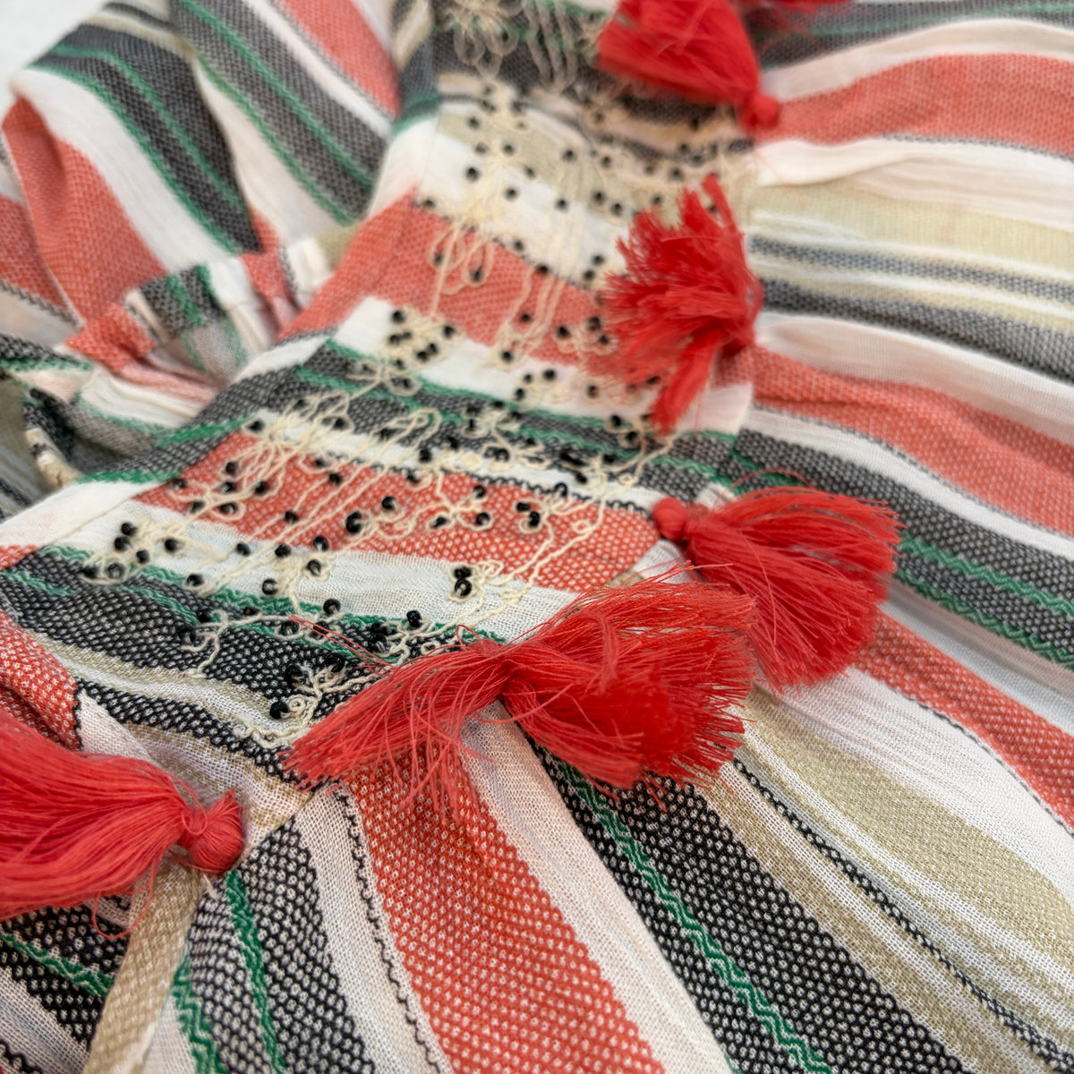 Summer Stripe Dress in coral striped viscose, close view of the beaded panel and coral tassels at the bust
