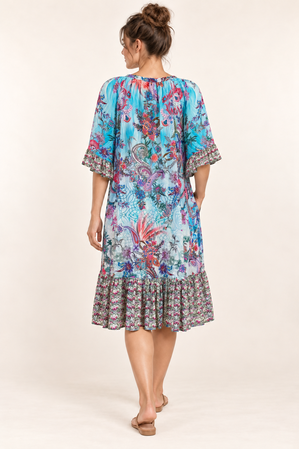 Turquoise Rhapsody Frill Dress, a blue floral and paisley viscose rayon dress, back view showing the gathered neckline and frilled hem.